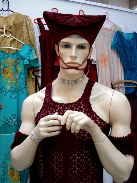 Mannequin med rød hat og mørkerød blondetop.